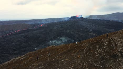 erupción volcánica fagradalsfjall en islandia con gente visitando el volcán - toma aérea de drones