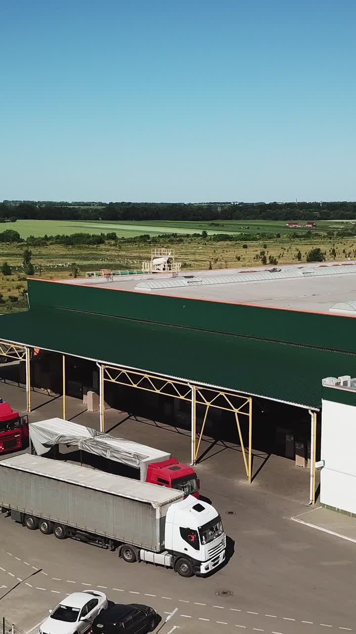 Aerial view of a big factory and a parking lot in the front. Vertical video