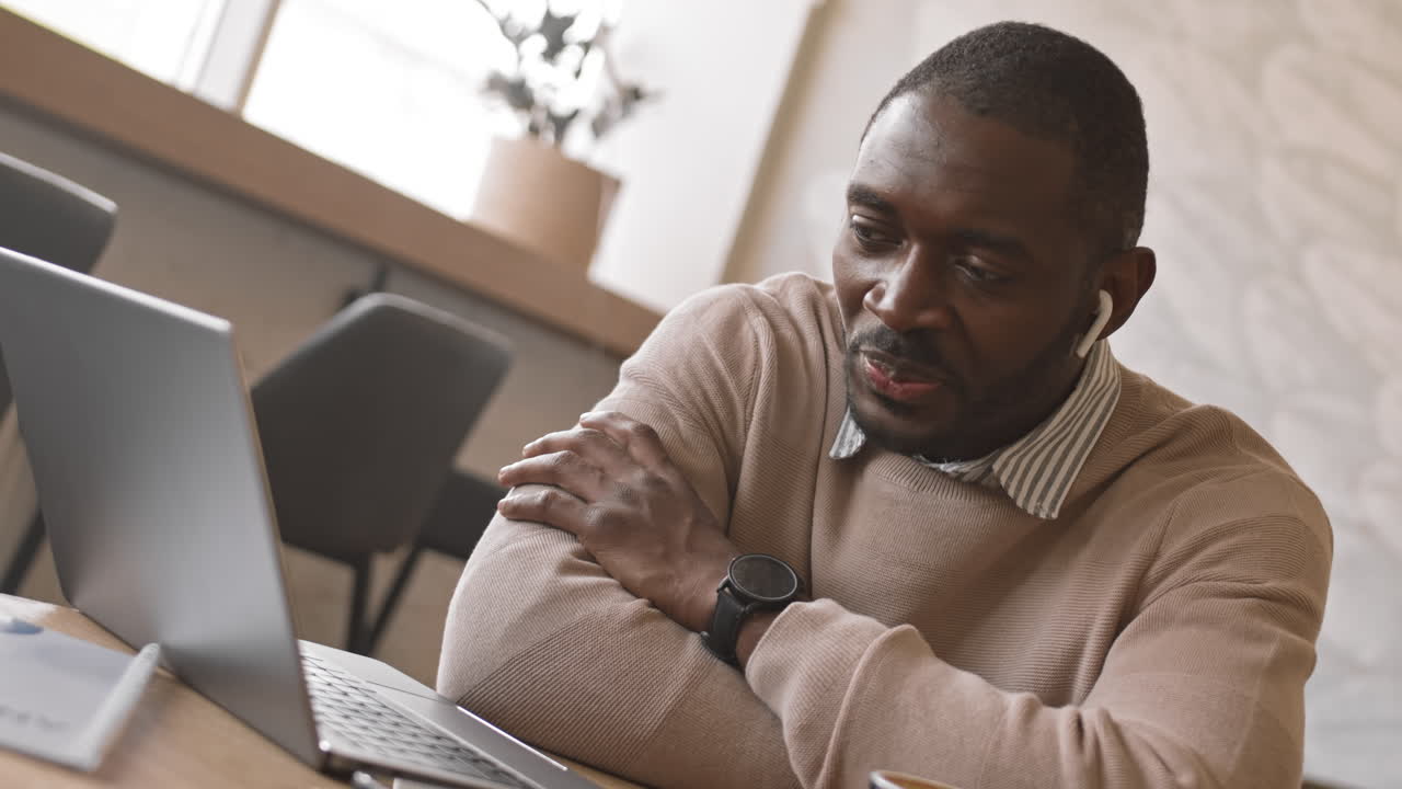 Uomo d'affari afroamericano in video chat con i colleghi in un bar