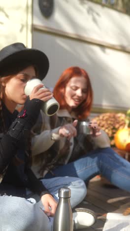 two friends enjoying drinks outdoors by a camper van