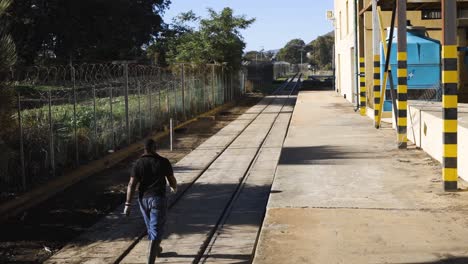 constructor caminando con confianza por vía férrea