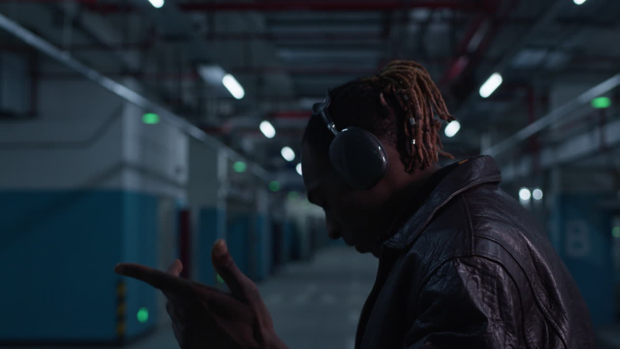 artista afroamericano rapero negro cantando y bailando solo en un estacionamiento subterráneo iluminado con luz de neón