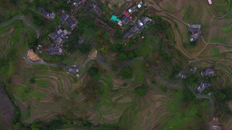 aerial drone shot of a peaceful village perched on a mountainside surrounded by lush greenery.