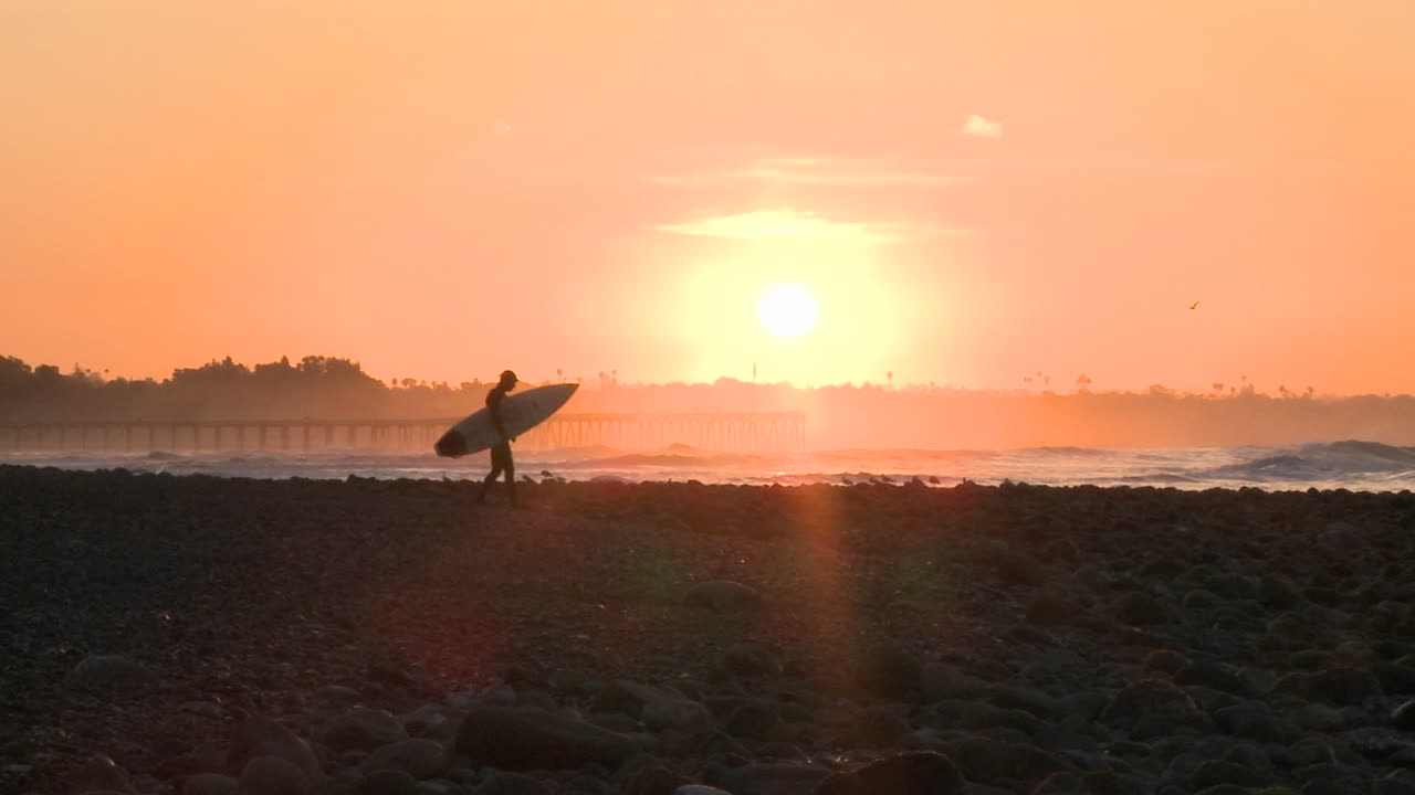 벤추라 캘리포니아의 서퍼 포인트에서 일출 동안 물에 들어가는 넓은 서퍼 실루엣
