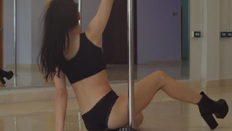 young sexy pole dancer in dancing boots looking at herself in the mirror while dancing