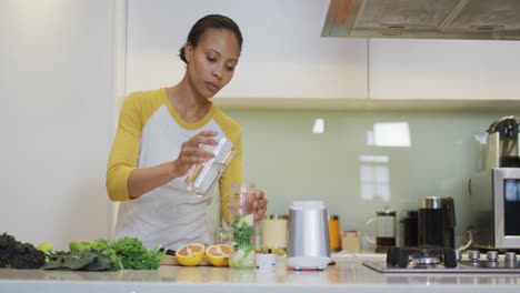 Mixed-race-woman-preparing-healthy-drink-in-kitchen