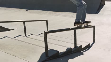 Low-section-of-caucasian-man-riding-and-jumping-on-skateboard-on-sunny-day