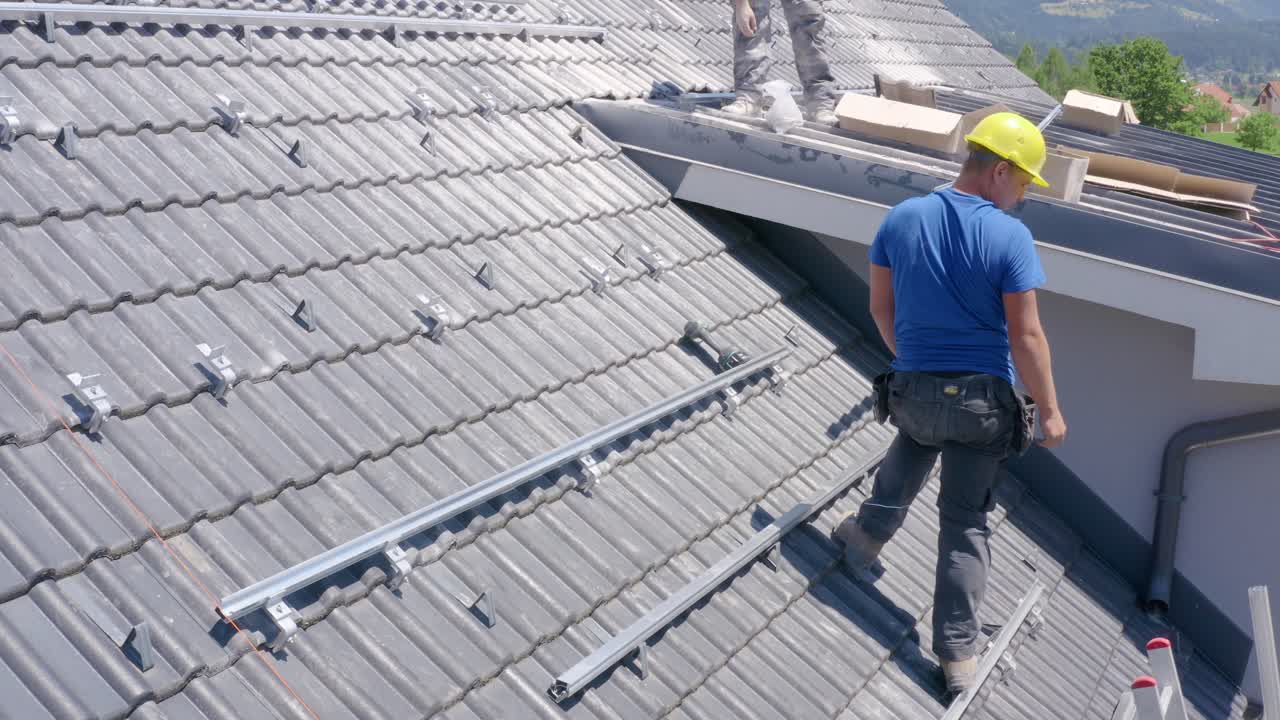 Young Slovenian worker on roof of house installing solar panels