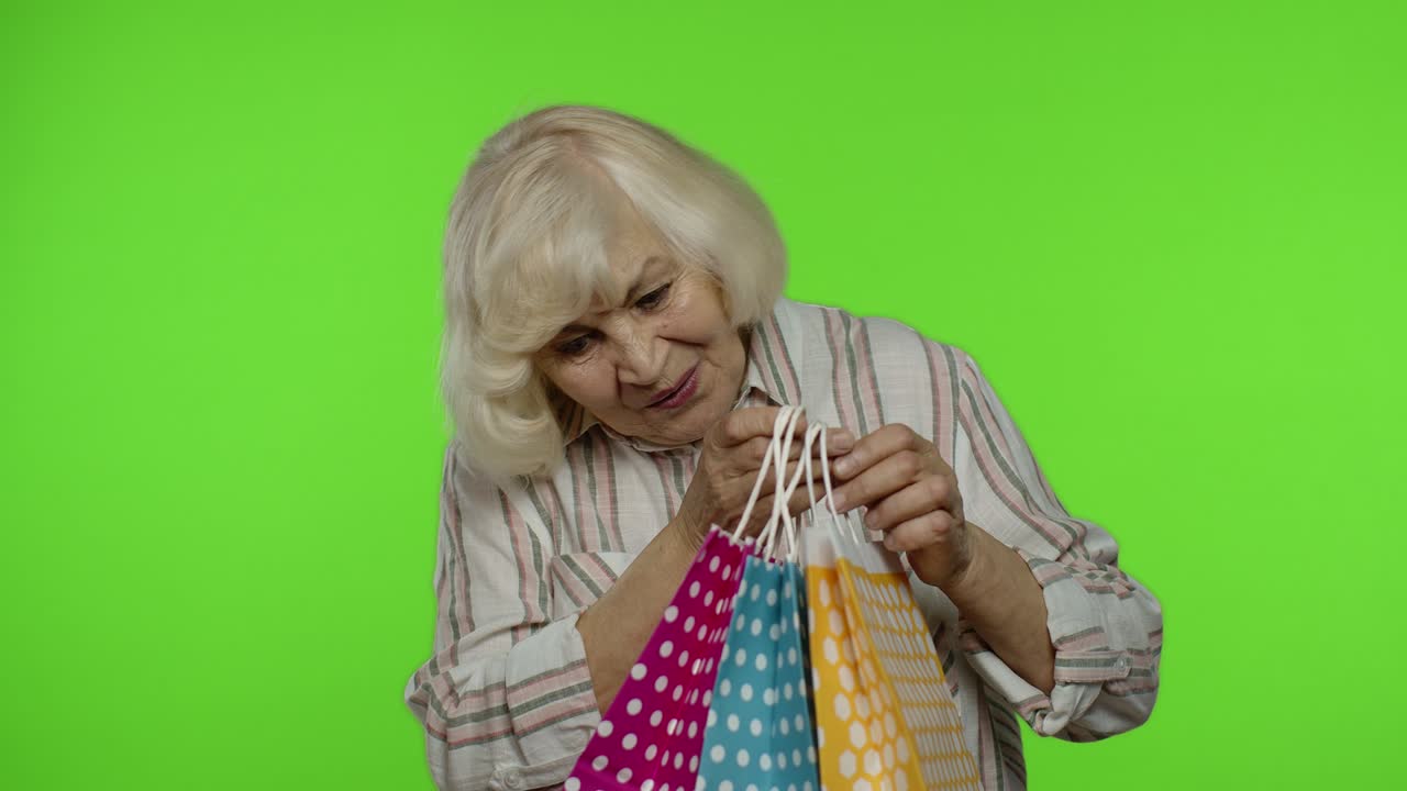 abuela mayor levantando bolsas de compras, celebrando, satisfecha con la compra, descuento. llave de croma