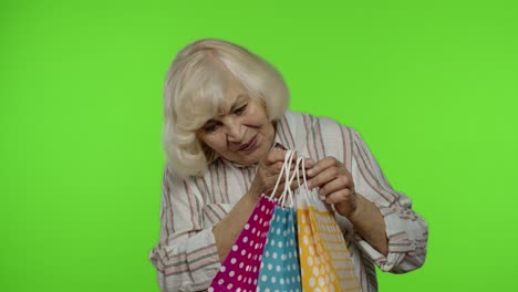abuela mayor levantando bolsas de compras, celebrando, satisfecha con la compra, descuento. llave de croma