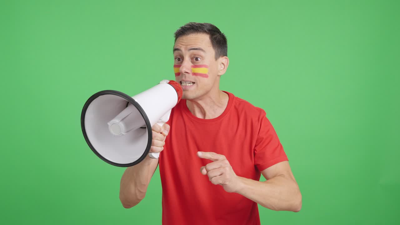 Uomo eccitato con la bandiera spagnola sulla faccia che usa un megafono
