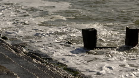 Mid-shot-of-waves-crashing-onto-groynes-and-sea-defences-at-Milford-on-Sea