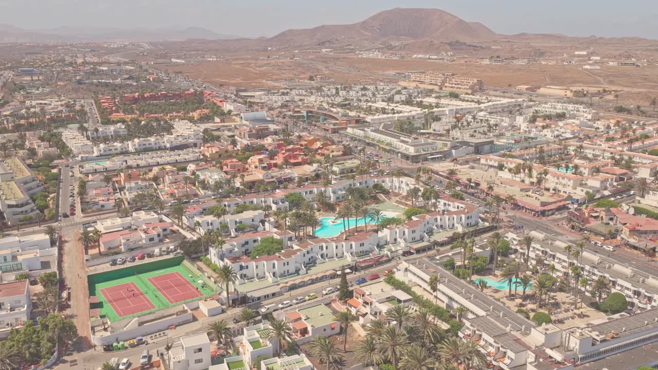 Panorama aereo che rivela architetture bianche, campo da tennis, piscine, palme su terreno vulcanico a Costa Calma, Fuerteventura, Isole Canarie, Spagna