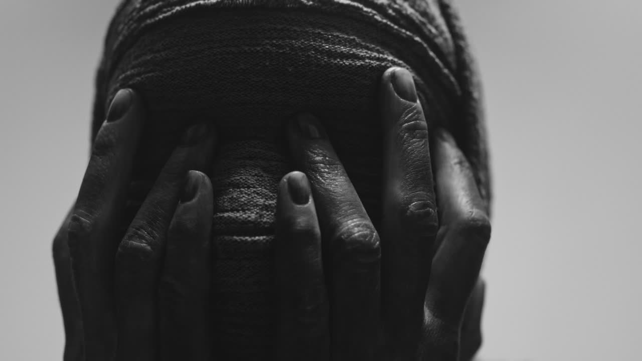 A mummified woman against the bright background in keeps her hands on her face the powerful pose full of despair