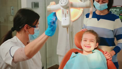 woman stomatologist technician lighting the lamp for examining little patient