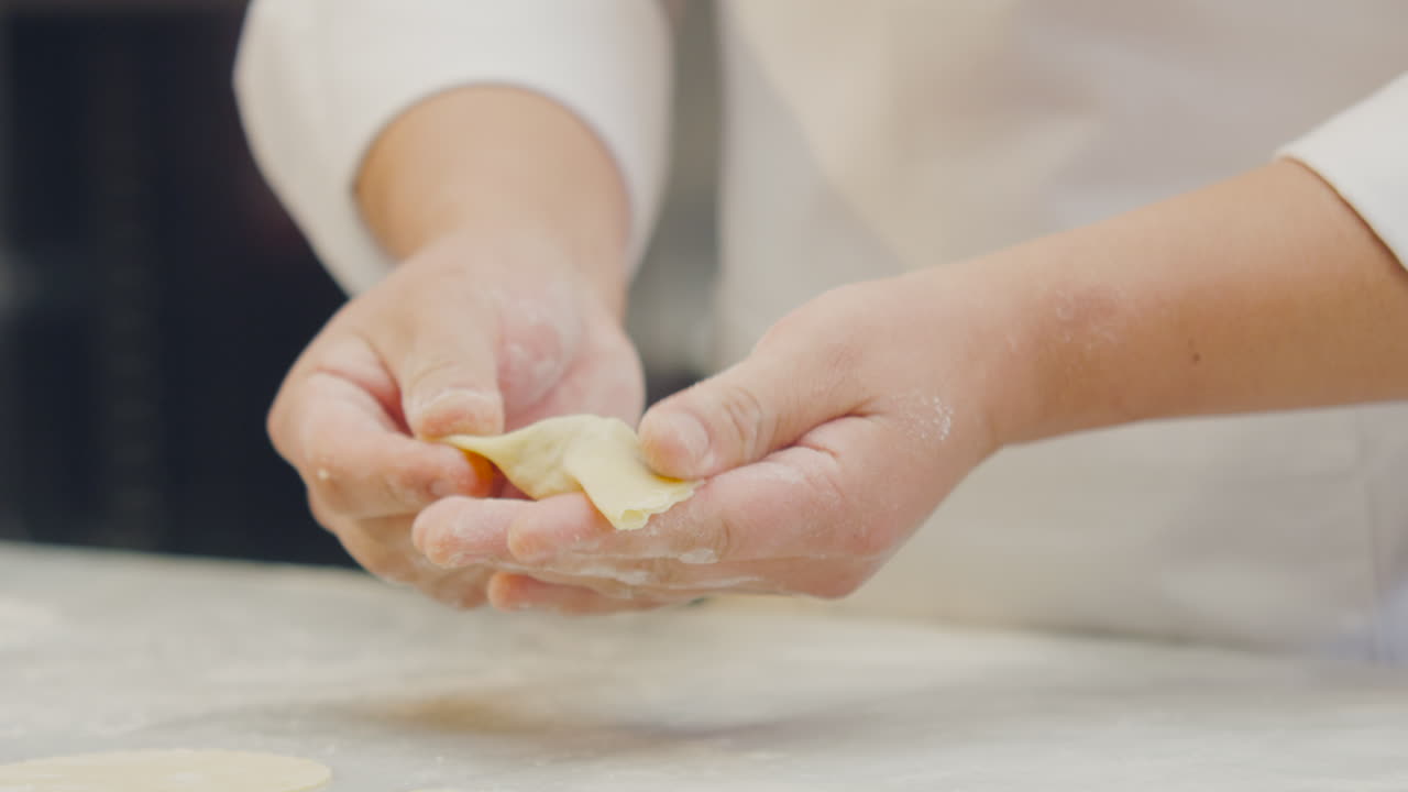 Close-up of a chef's hands forming a ravioli and placing it with culinary artistry