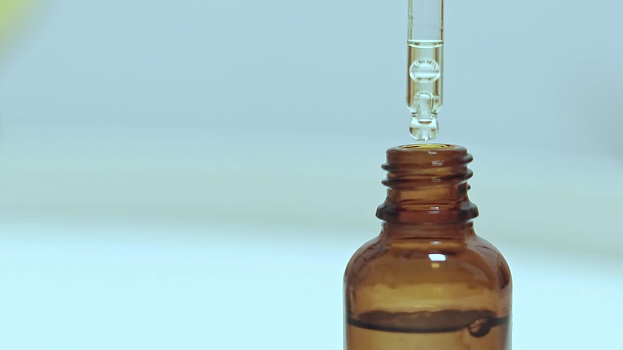 Selective focus to showcasing a glass bottle dropper containing organic serum, skincare and wellness product