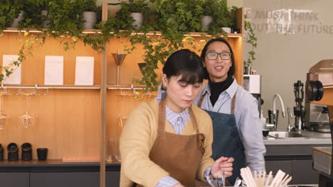 Two-Waiters-Working-Behind-Bar-Counter,-Then-Smiling-And-Waving-At-Camera