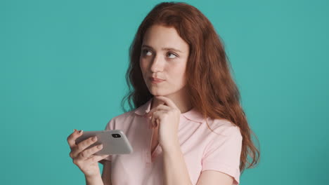 redheaded girl in front of camera on turquoise background.