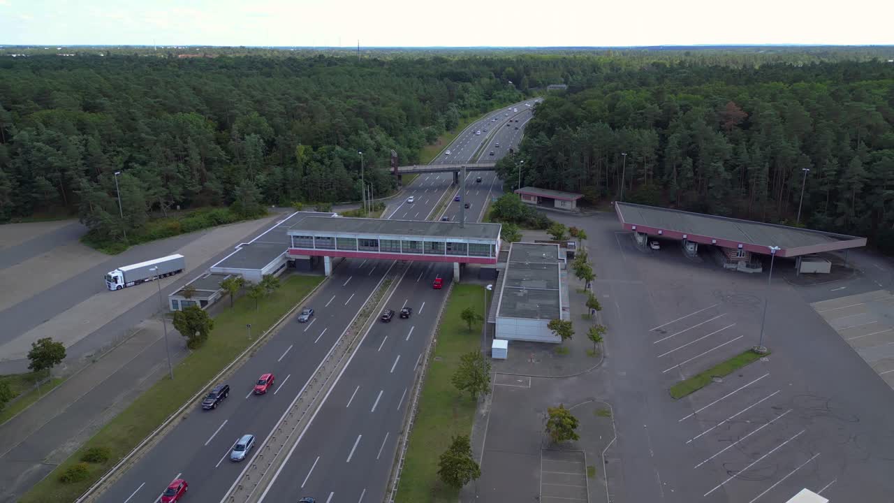 highway rest stop with cars driving on a multi lane highway. wide orbit overview drone