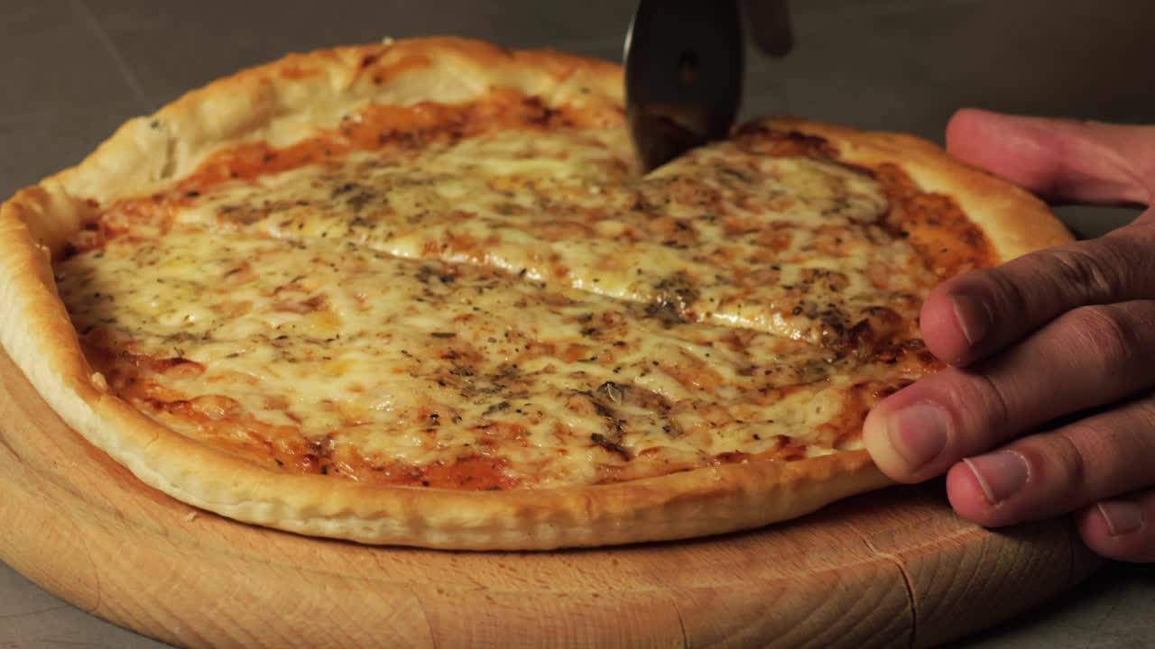 Tagliare una pizza fresca e filante con una rotella tagliapizza, mostrando la crosta croccante e il formaggio fuso. Perfetto per illustrare la preparazione della pizza fatta in casa e il comfort food italiano