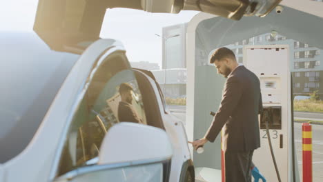 hombre de negocios cargando vehículo eléctrico