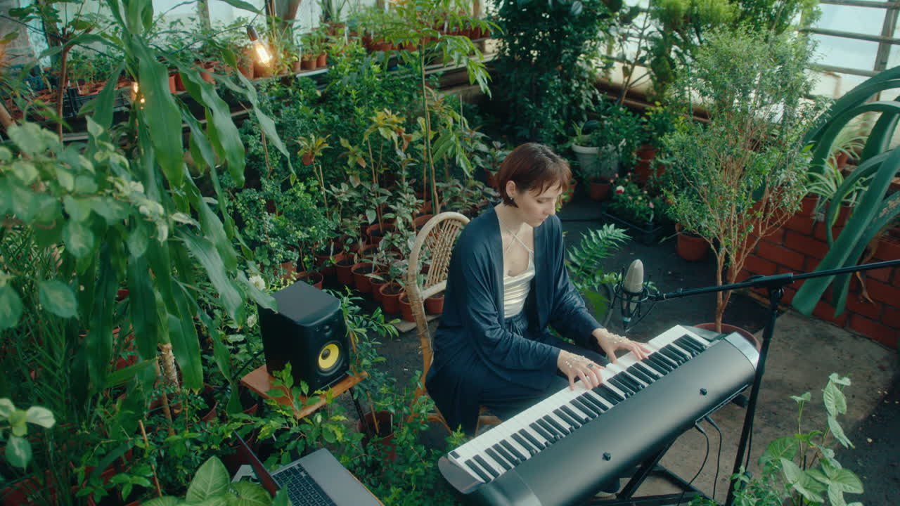 Female Music Artist Surrounded by Plants Playing Keyboard in Greenhouse