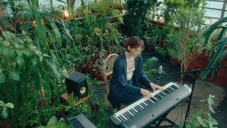 Female Music Artist Surrounded by Plants Playing Keyboard in Greenhouse