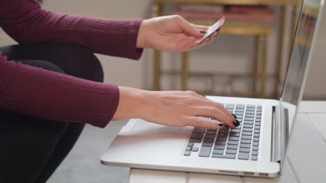 slow motion shot of woman typing in card details into laptop and gives thumbs up when she completes purchase