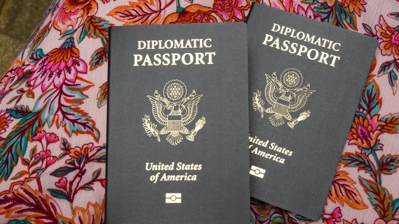 Two black United States diplomatic passports on floral background, close up