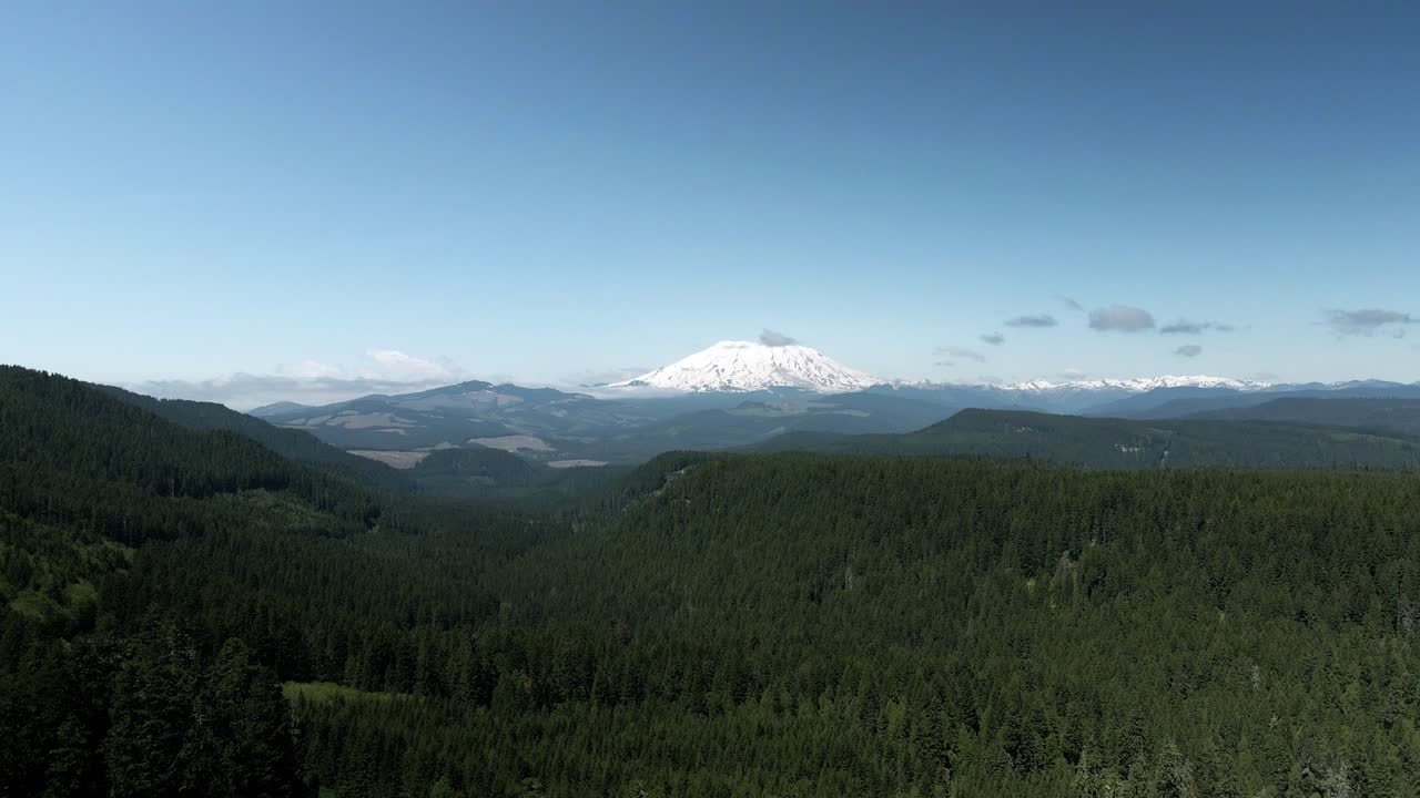 Mostly clear blue skies over snow capped Mount Saint Helens, Washington State, aerial track back