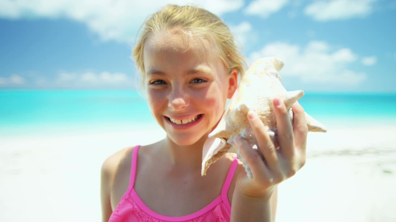 Ritratto di ragazza sulla spiaggia con una conchiglia.