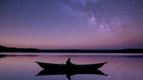 Silhouette of a person in a boat under a starry sky, captured from a low angle