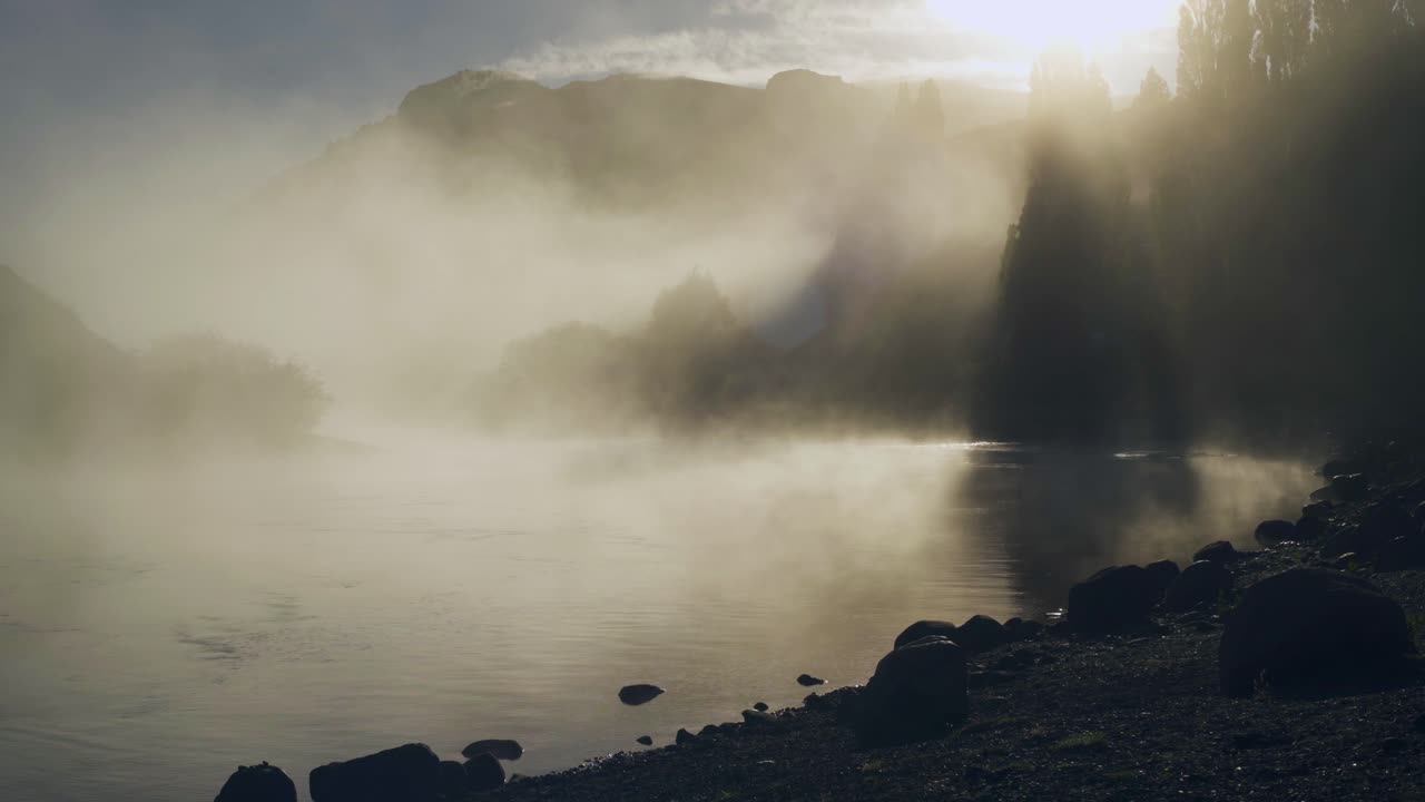 Sunlight shining through dense fog moving over Limay River in Patagonia, Argentine.