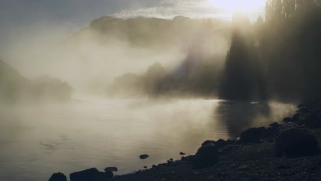 sunlight shining through dense fog moving over limay river in patagonia, argentine.