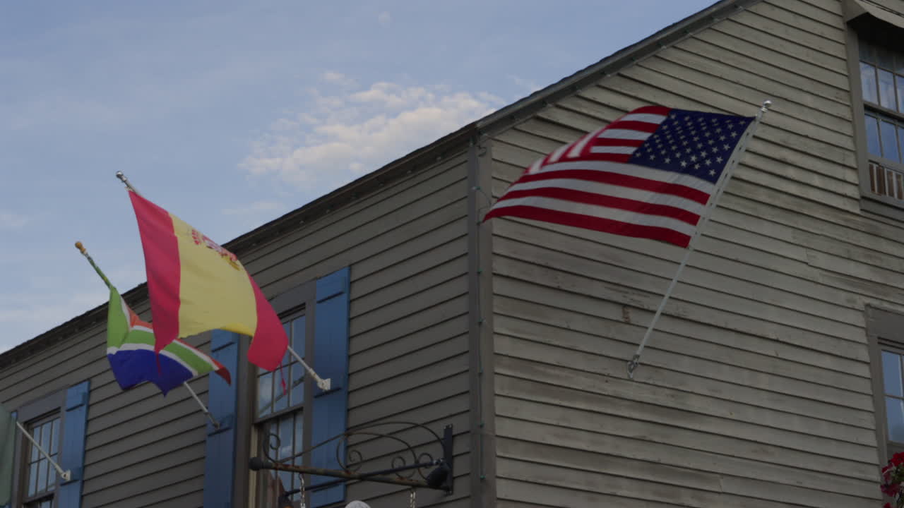 Hanging Spain And American Flags At Wooden House Exterior In St. Augustine, Florida, USA. Low Angle Shot