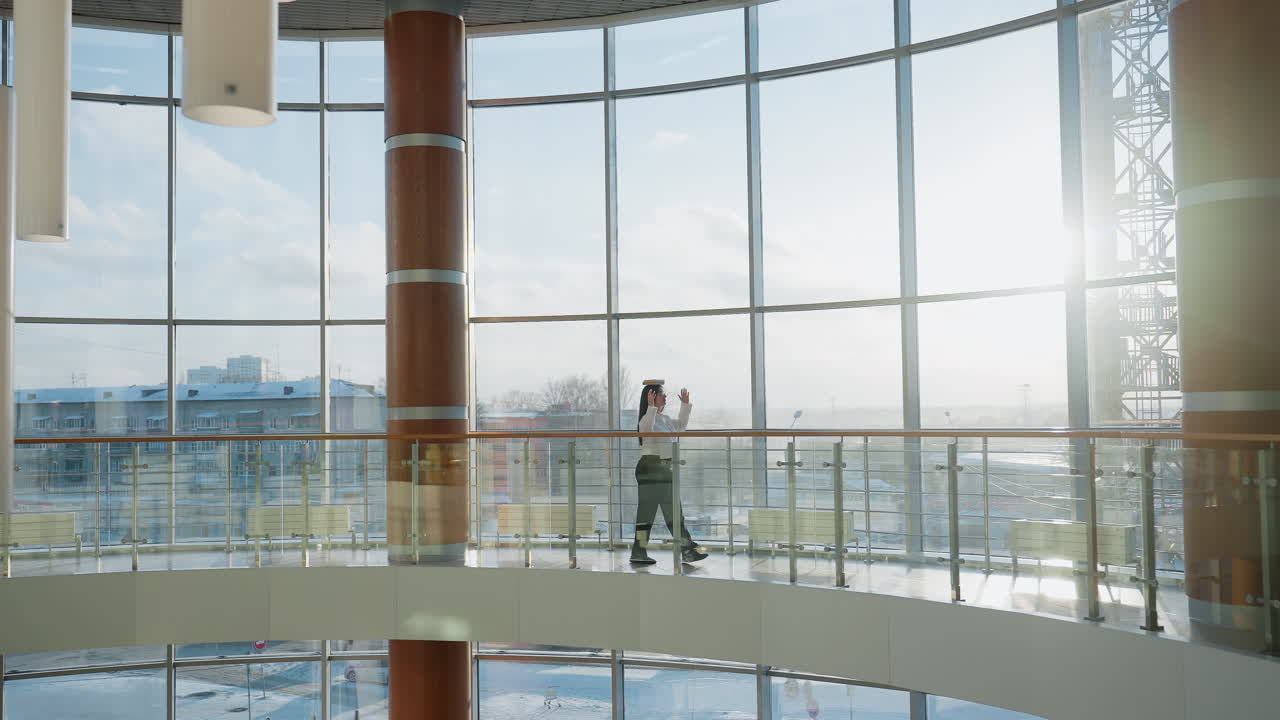 Modern spacious mall interior with panoramic glass windows and natural sunlight as elegant woman walks slowly balancing book on head, arms raised gently to maintain balance and avoid dropping book