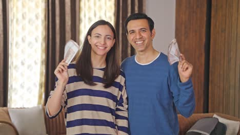 happy indian couple using money as fan