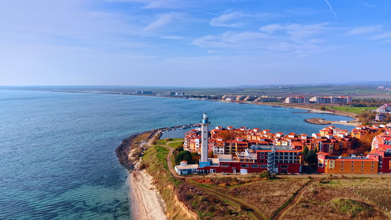 Accogliente zona residenziale colorata con faro adiacente sulla riva del mare. Prospettiva aerea sulla costa soleggiata del Mar Nero e complesso Marina Cape ad Aheloy, Bulgaria