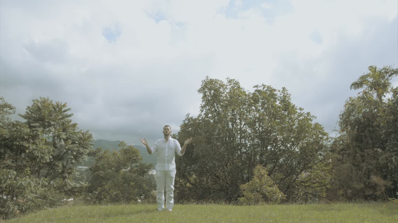 Young man in white Dress doing yoga meditation and spiritual movements in a beautiful green landscape mindfulness and tai chi