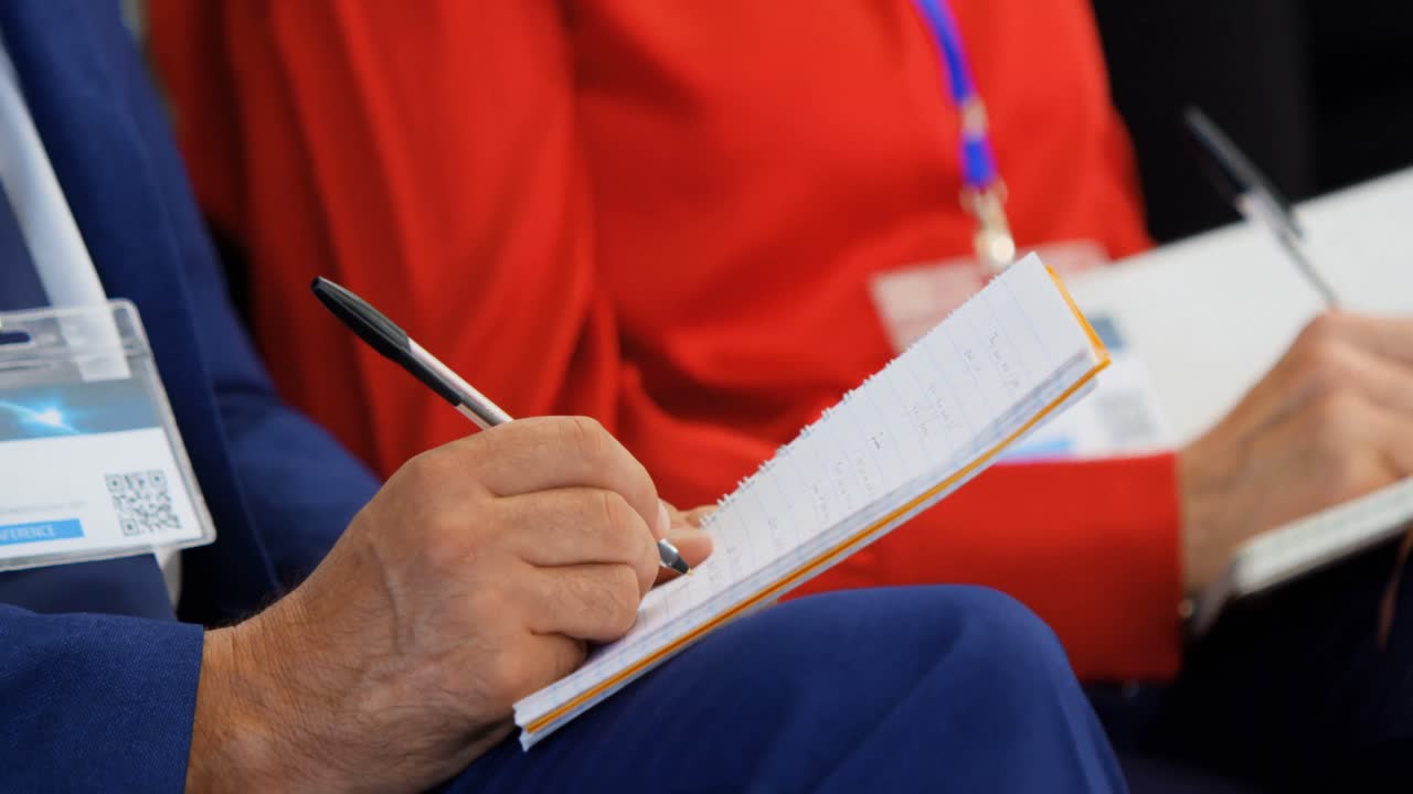 비즈니스 세미나 4k에서 노트패드에 글을 쓰는 비즈니스 사람들