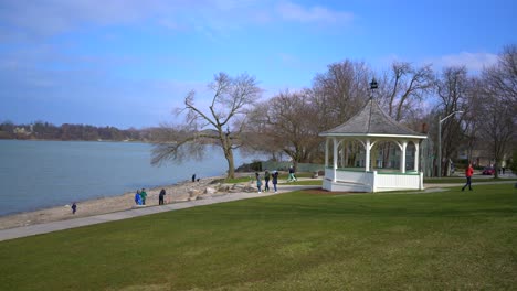 gazebo at niagara-on-the-lake near beach and lake view on beautiful bright day with bright blue sky with people enjoying life and walking around with grass and sand