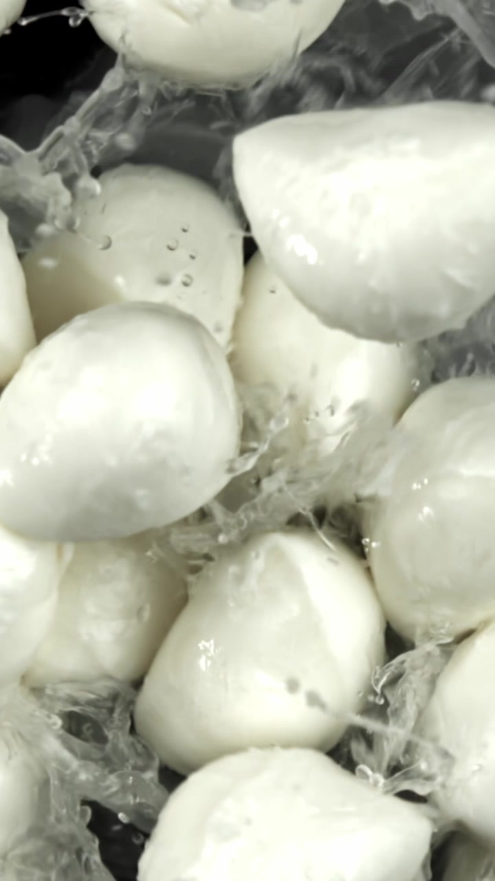 Acqua che schizza su palline di mozzarella fresca al rallentatore