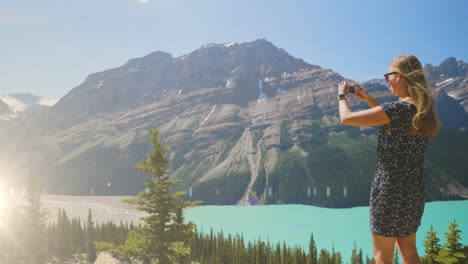 animation of light over caucasian woman taking pictures of mountain landscape