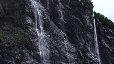 Norway-landscape,-big-waterfall-close-up-moving-down-the-rocks-with-green-forest-below