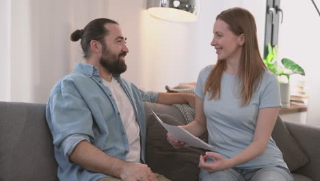 bearded man and beautiful woman have a relaxed conversation sitting on the sofa