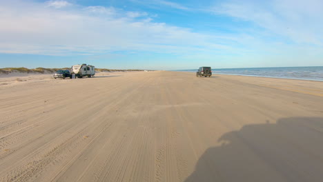 POV-from-top-of-a-slowly-driving-vehicle-on-the-beach-while-another-vehicle-passes