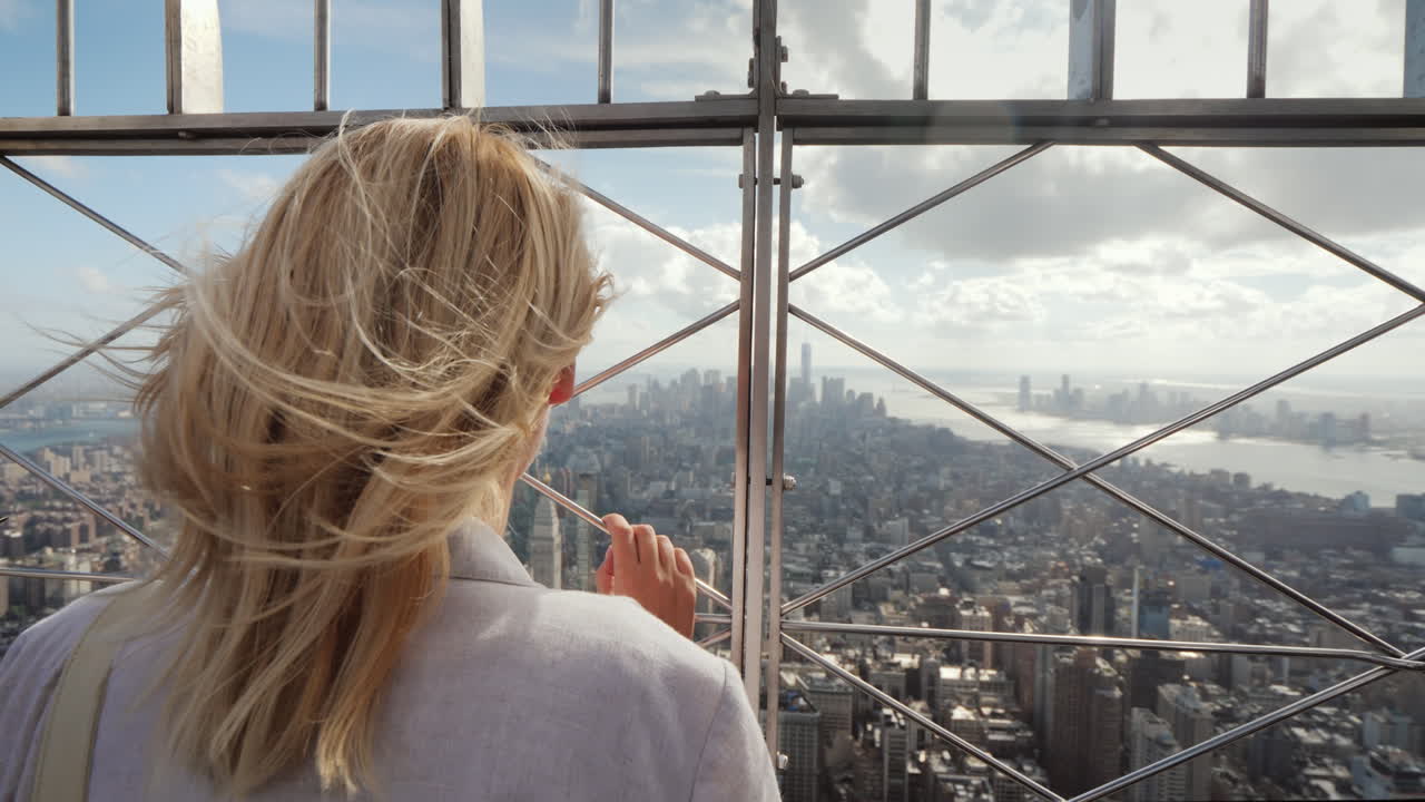 la mujer mira la metrópolis debajo de ella se encuentra en la vista trasera de la valla en el cielo visible a distancia