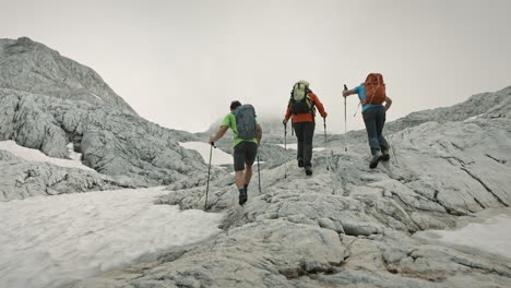 hikers wearing backpack and using hiking poles to walk on the inclines of a climb of a mountain