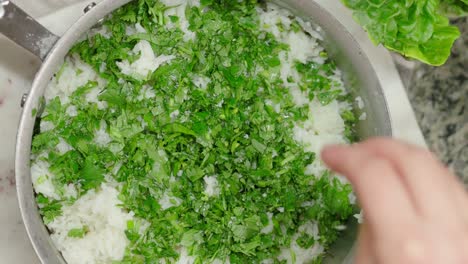 a pot of freshly cooked rice garnished with chopped herbs in a kitchen setting